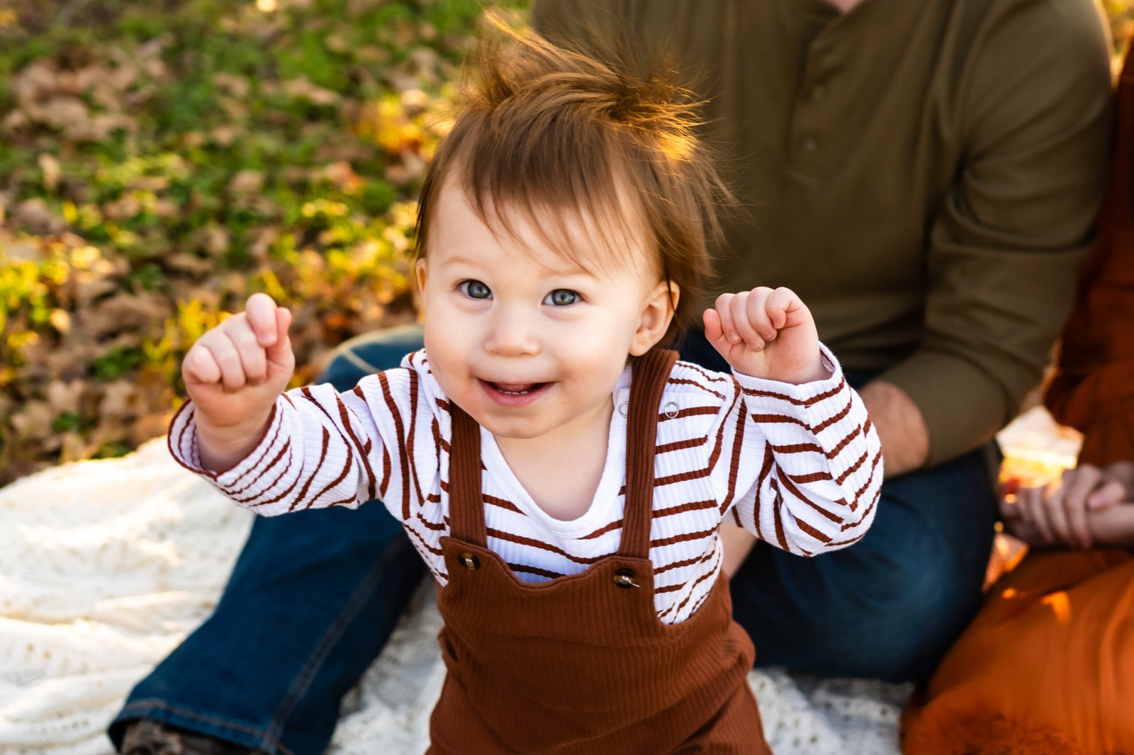 Close up of one year old boy in rust colored overalls walking at Green Acres Farm Memorial Park in Flower Mound, Texas.
