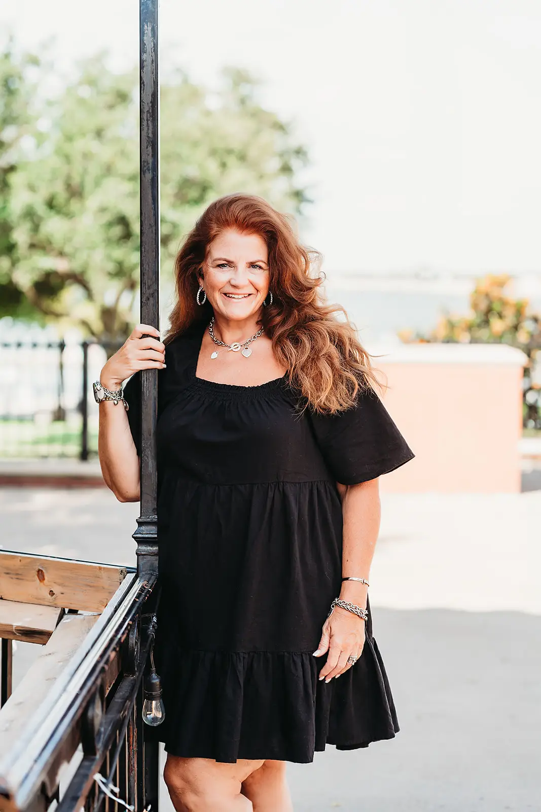 Lady holding on to light pole posing at Rockwall Texas Harbor for headshot photography.
